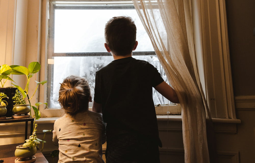 Two kids looking out a window  