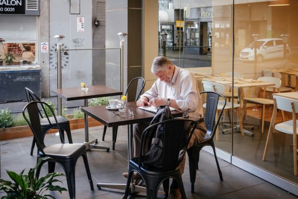 Man in white shirt sitting in Melbourne cafe reading the newspaper