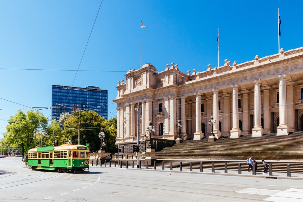 image a tram running on the street in front of the Victorian Parliament House  