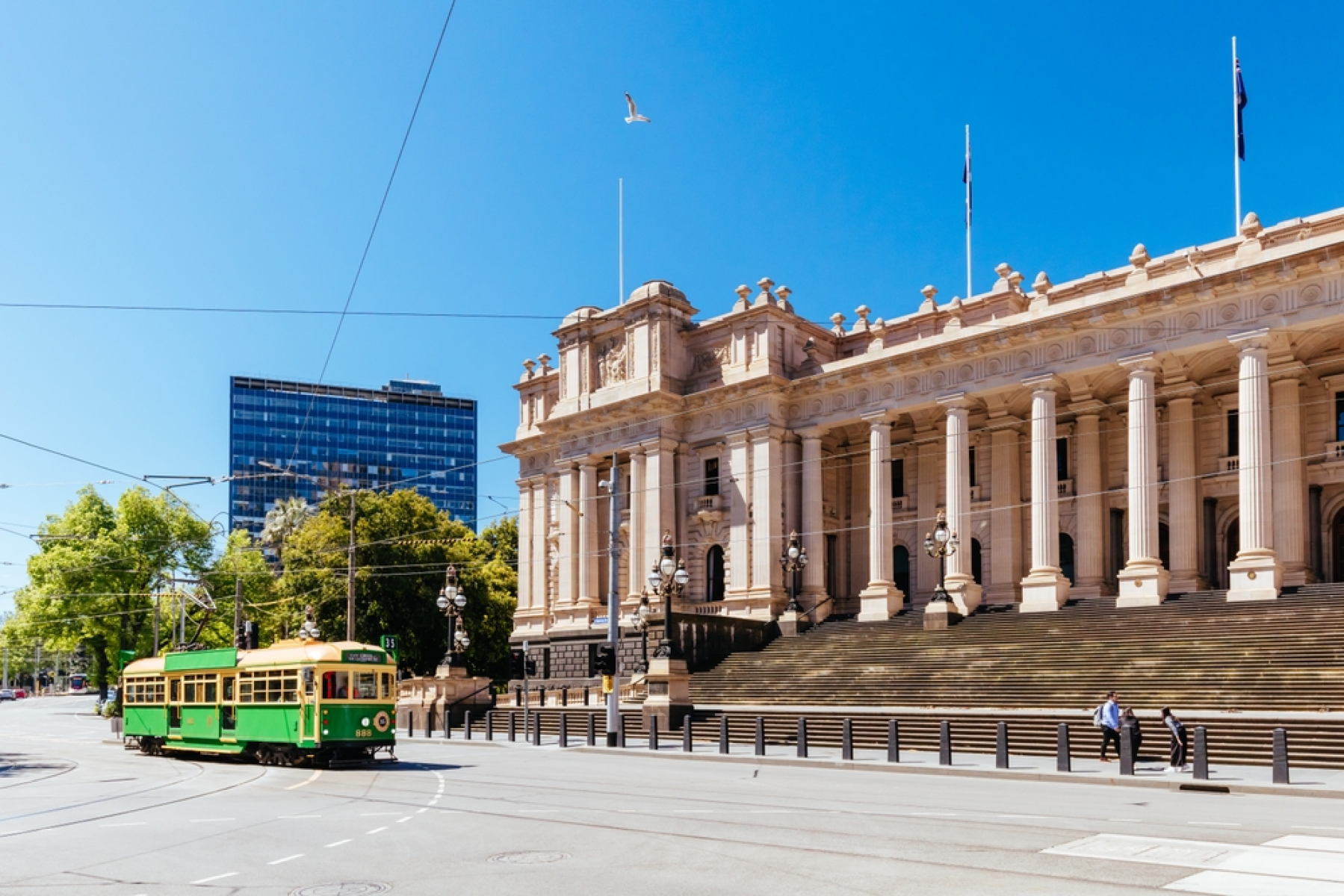 image a tram running on the street in front of the Victorian Parliament House