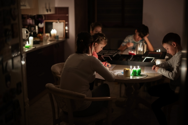 Family spending time together during an energy crisis causing blackouts. Kids drawing in blackout.