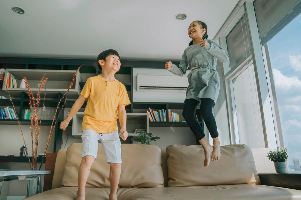 2 children playing in comfort in family room with air conditioner running  