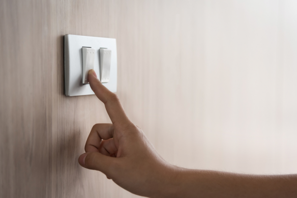 Close up of male finger turning on light switch on a wooden wall at home